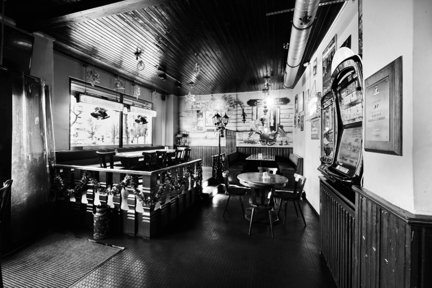 Ein schwarz-weiß Foto zeigt das Innere einer traditionellen Bar mit Tischen und einer Jukebox.