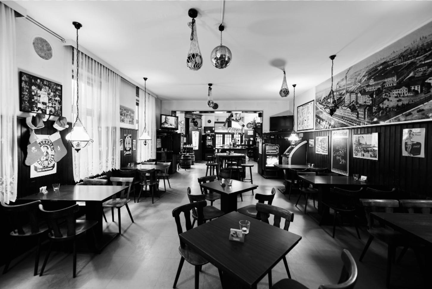 Ein großes Café mit vielen Tischen und Stühlen, dekoriert mit nostalgischen Wandbildern und Lichterketten.