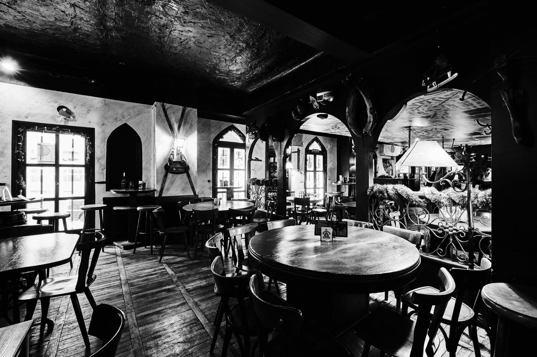 Ein historisch anmutendes Gasthaus zeigt antike Möbel und dekorative Beleuchtung in Schwarz-Weiß.