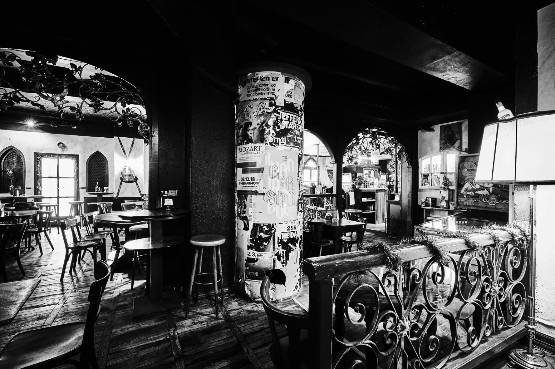 Ein historisches Café mit schmiedeeisernen Verzierungen und einem beklebten Werbesäulen-Mittelpunkt.
