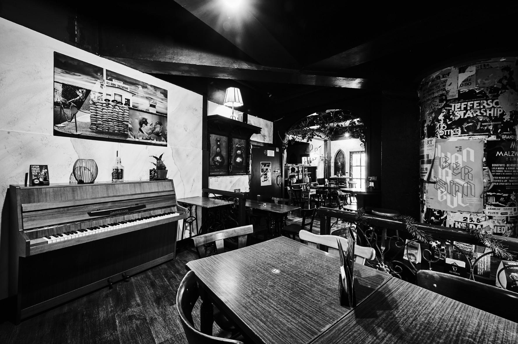 Eine gemütliche Bar im Vintage-Stil mit Holzmöbeln, Klavier und dekorativen Bildern.