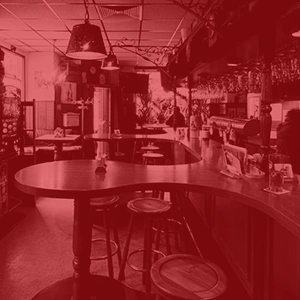 Foto einer Bar mit Tischen, Hockern und Lampen an der Decke.