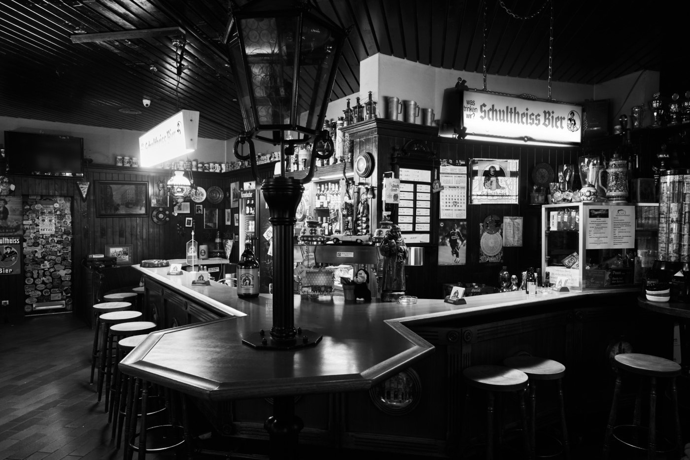 Eine traditionelle Bar ist in Schwarzweiß abgebildet mit Hockern und einer Vielzahl von Dekorationen.