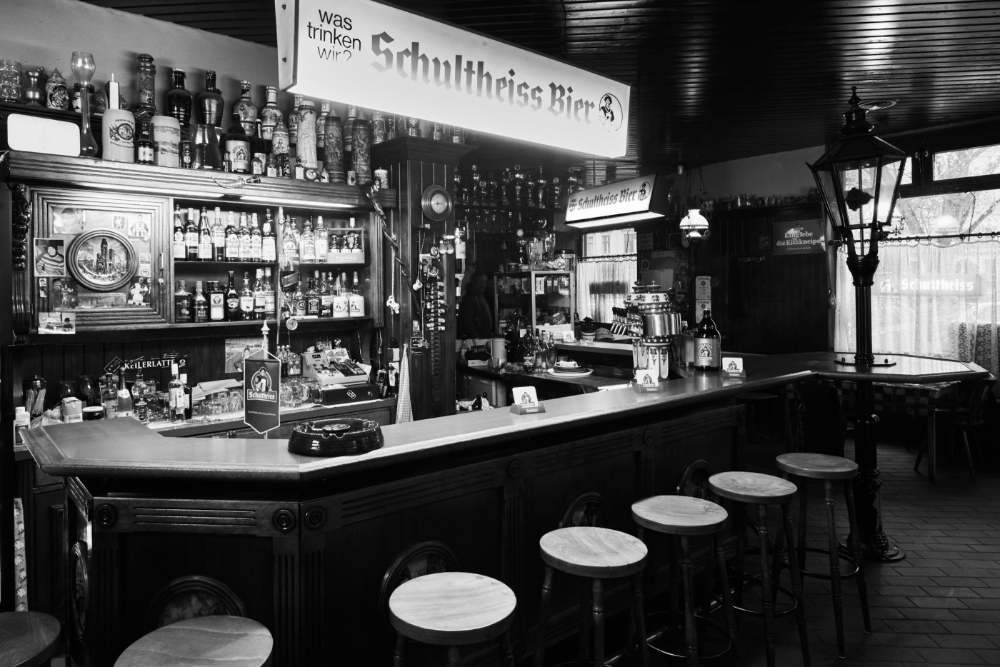 Eine traditionelle Bar mit holzverkleideter Theke und Regalen voller Getränkeflaschen.