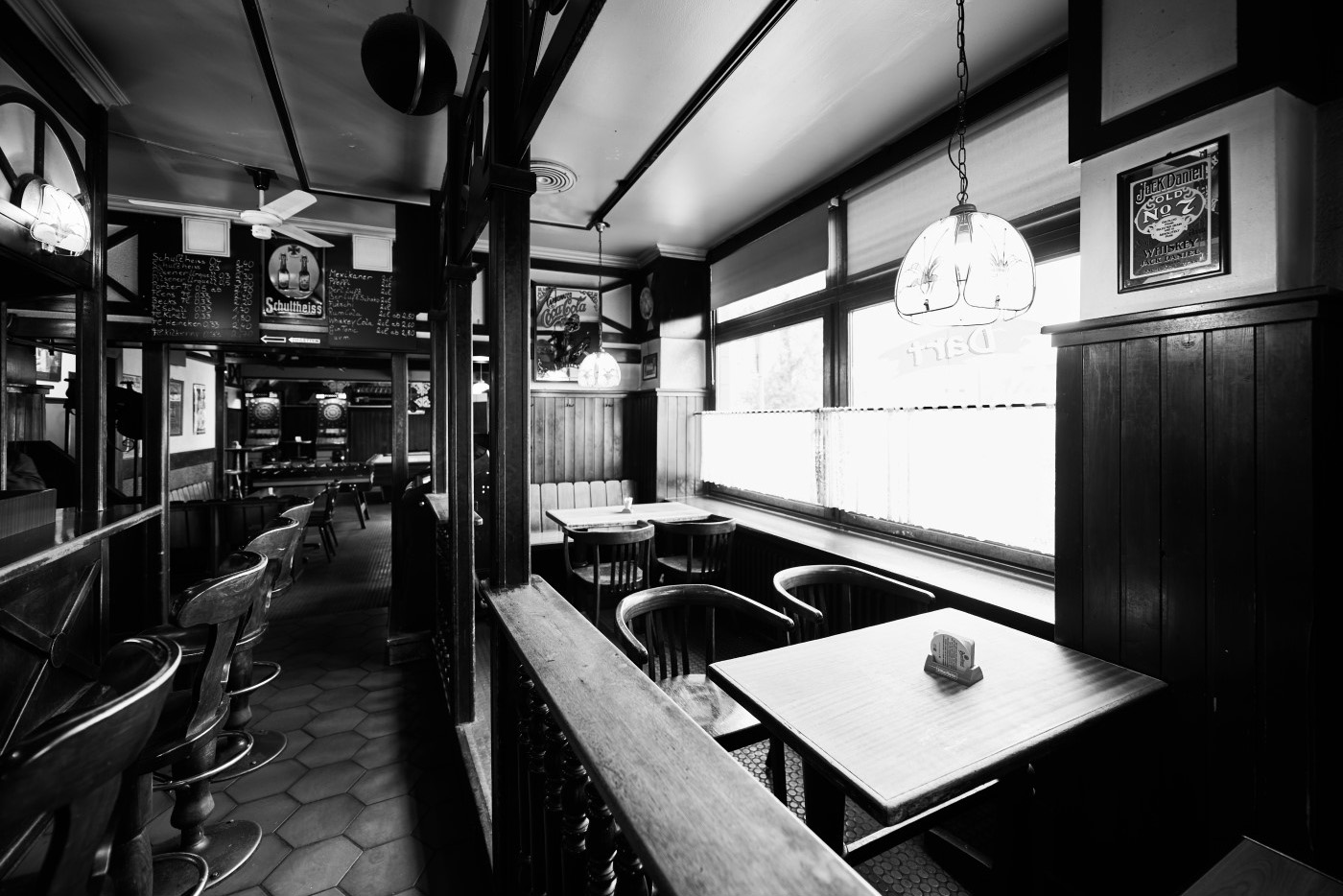 Innenaufnahme eines leeren Pubs mit Holzmöbeln und dekorativen Lampen.
