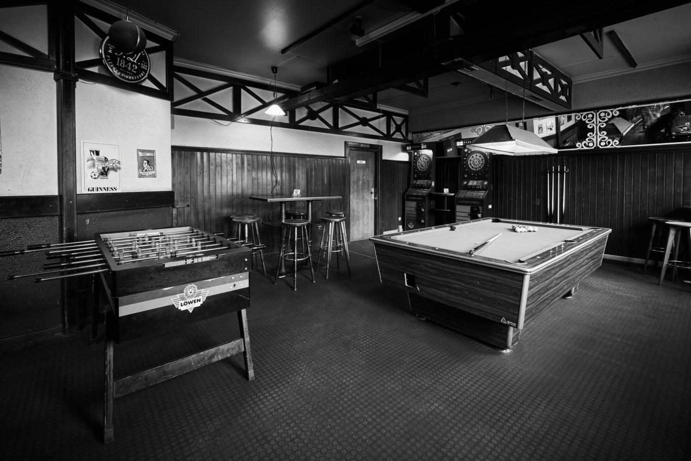 Ein Tischfußball und ein Billardtisch stehen in einer dunkelholzgetäfelten Bar.